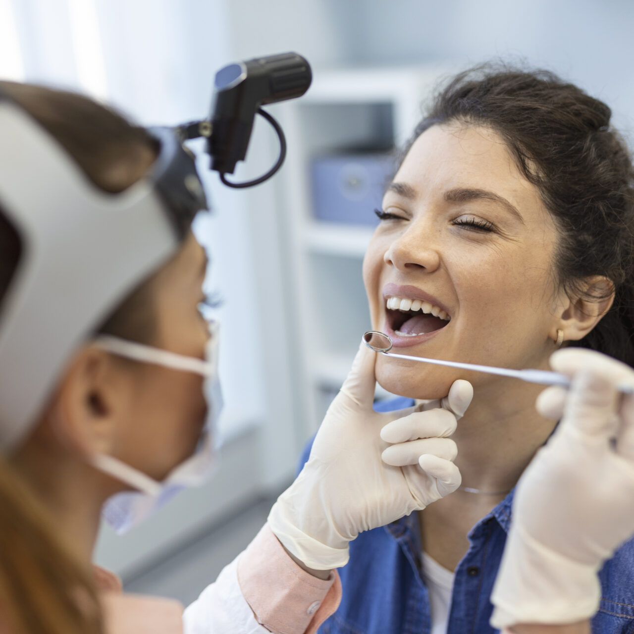 Female patient opening her mouth for the doctor to look in her throat. Otolaryngologist examines sore throat of patient.